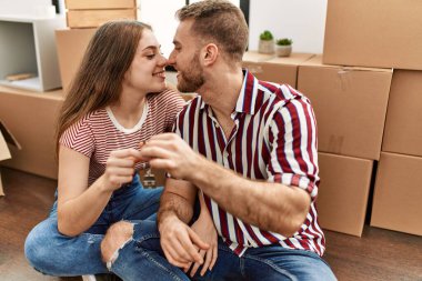 Genç beyaz çift gülümsüyor. Yeni evin anahtarını tutuyorlar..