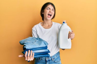 Çamaşırlarını yıkayan beyaz bir kadın çamaşır deterjanı şişesi ve katlanmış kotla kızgın ve öfkeli bağırıyor öfkeyle bağırıyor.. 