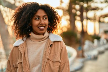 Genç Afrikalı Amerikalı kadın gülümseyerek şehirde mutlu mesut duruyor..