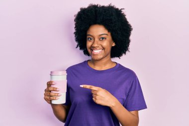 Genç Afrikalı Amerikalı kadın elinde kahveyle mutlu mesut elini ve parmağını gösterdi. 