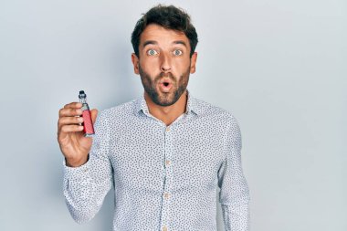 Sakallı, futbol muhabiri elinde elektronik sigarayla yakışıklı bir adam ağzı açık kalmış, korkmuş ve şaşkın bir şekilde şaşırmış. 