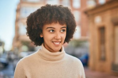 Genç İspanyol kız gülümseyerek şehirde mutlu mesut dikiliyor..