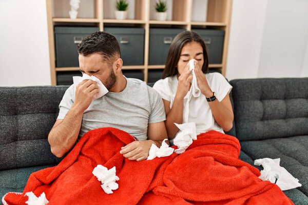 Young latin ill couple using napkin sititng on the sofa at home.