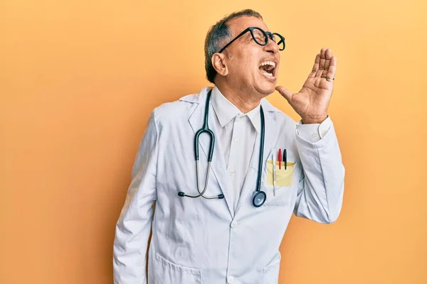 医師のコートと聴診器を身に着けている中年のインド人男性は大声で叫び 口の上で手で横に叫んでいます コミュニケーションの概念 — ストック写真