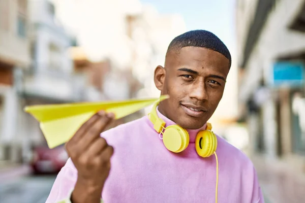 市内で紙飛行機を持っているヘッドフォンを使用して若いアフリカ系アメリカ人 — ストック写真