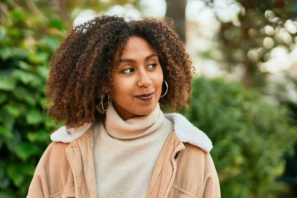 Genç Afrikalı Amerikalı kadın parkta mutlu bir şekilde gülümsüyor..