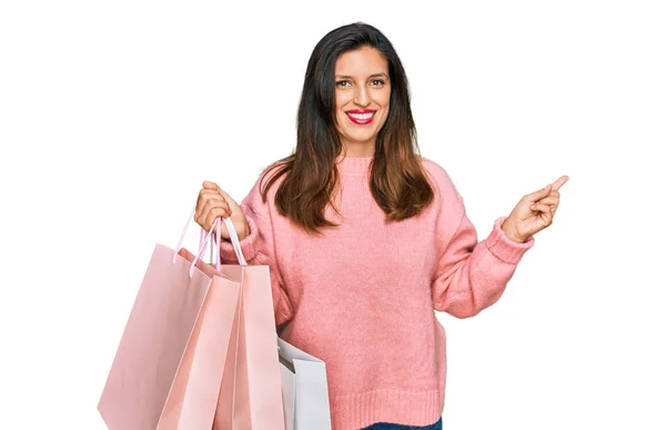 Beautiful Hispanic Woman Holding Shopping Bags Smiling Happy Pointing Hand — Stock Photo, Image