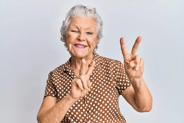 Starsza Siwowłosa Kobieta Luźnych Ciuchach Uśmiechnięta Kamery Pokazująca Palce Robiące — Zdjęcie stockowe