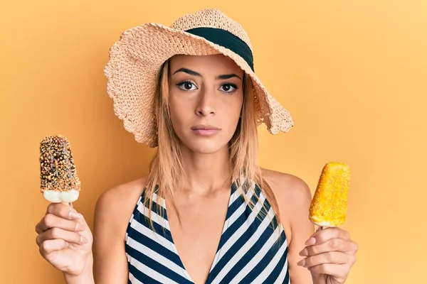 顔に深刻な表情でリラックスしたアイスクリームを保持夏のスタイルを身に着けている美しいブロンドの女性 カメラを見ているだけで — ストック写真