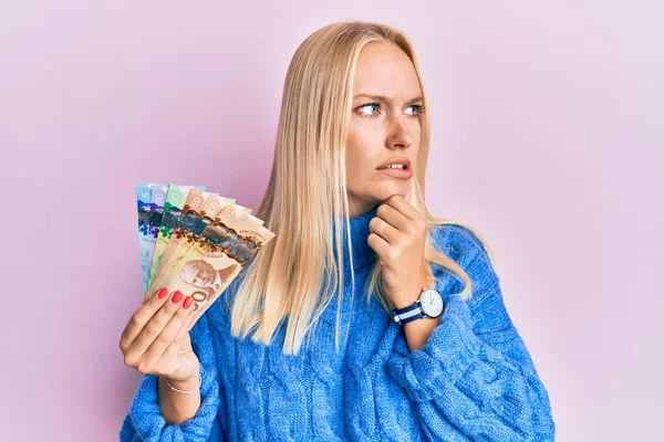 Young Blonde Girl Holding Canadian Dollars Thinking Worried Question Concerned — Stock Photo, Image