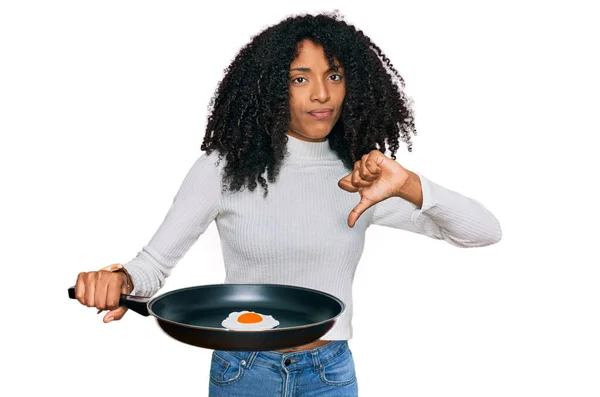 若いですアフリカ系アメリカ人の女の子保持スキルとともに揚げ卵とともに怒っている顔 否定的な兆候ショー嫌いで親指ダウン 拒絶概念 — ストック写真