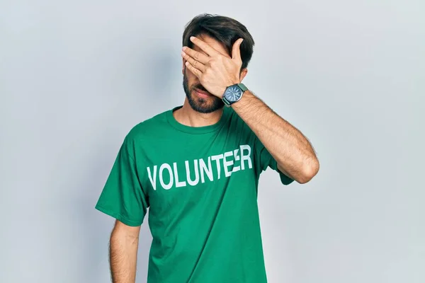 Jovem Hispânico Vestindo Camiseta Voluntária Cobrindo Olhos Com Mão Parecendo — Fotografia de Stock