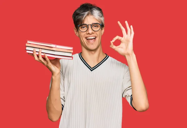 Young Hispanic Man Holding Books Doing Sign Fingers Smiling Friendly — Stock Photo, Image