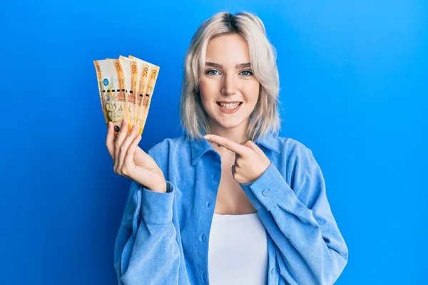 Young Blonde Girl Holding Philippine Peso Banknotes Smiling Happy Pointing — Stock Photo, Image