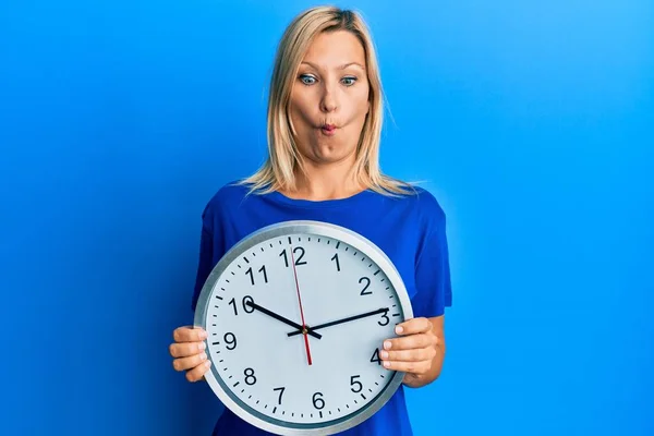 Beautiful Middle Age Blonde Woman Holding Big Clock Making Fish — Stock Photo, Image