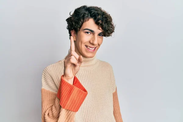 Latynoski Młody Człowiek Luźnym Zimowym Swetrze Pokazuje Wskazuje Palcem Numer — Zdjęcie stockowe