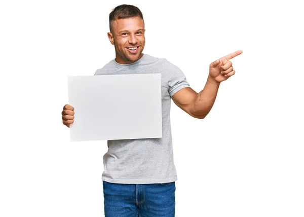 Hombre Musculoso Guapo Sosteniendo Pancarta Vacía Sonriendo Feliz Señalando Con — Foto de Stock