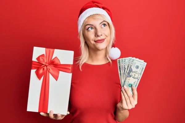 Молода Блондинка Різдвяному Капелюсі Тримає Подарунок Долари Посміхається Дивлячись Бік — стокове фото
