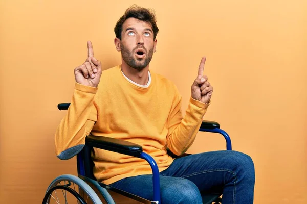 Handsome Man Beard Sitting Wheelchair Amazed Surprised Looking Pointing Fingers — Stock Photo, Image