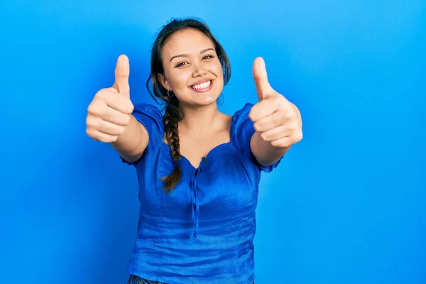 手で積極的なジェスチャーを行うことを承認カジュアル服を着て若いヒスパニック系の女の子 親指アップ笑顔と成功のために幸せ 勝者のジェスチャー — ストック写真