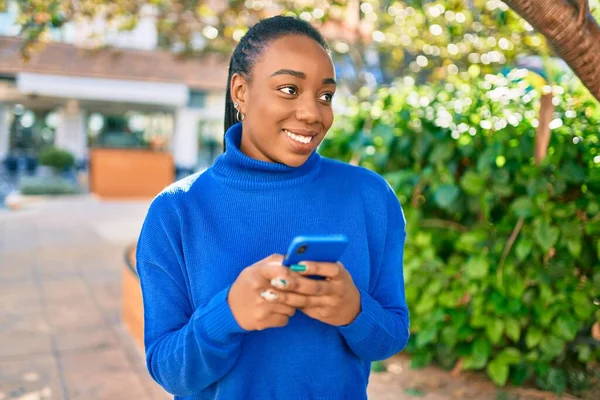 若いアフリカ系アメリカ人の女性が公園でスマートフォンを使って笑顔で幸せ — ストック写真