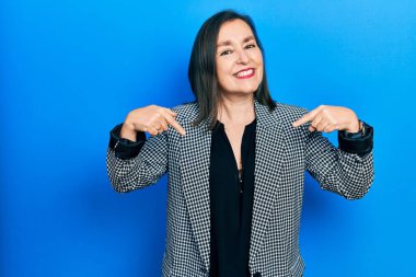 Orta yaşlı İspanyol kadın iş kıyafetleri giyiyor. Kendine güveni tam görünüyor. Kendini gururlu ve mutlu gösteriyor.. 