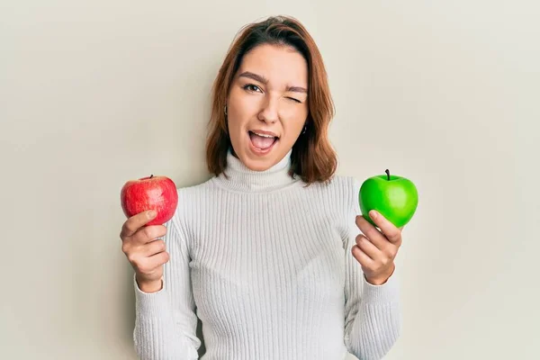 Junge Kaukasische Frau Mit Rotem Und Grünem Apfel Zwinkernd Die — Stockfoto
