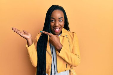 Genç Afrikalı Amerikalı kadın, sıradan bir ceket giyiyor kameraya hayret ediyor ve gülümsüyor.. 