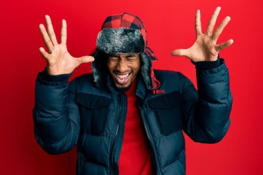 Sakallı, kışlık şapkalı ve paltolu genç Afro-Amerikan adam kollarını kaldırmış ve gözleri kapalı heyecanla haykırarak başarının çılgınlığını kutluyor. Kazanan konsept 