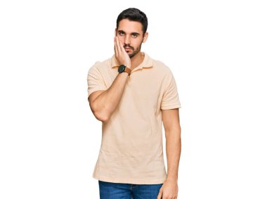 Günlük kıyafetler giyen genç İspanyol adam kollarını kavuşturarak depresyondan sıkılmış ve yorgun görünüyor.. 