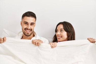 Genç İspanyol çift yatakta yatıp çarşafla örtüyor..