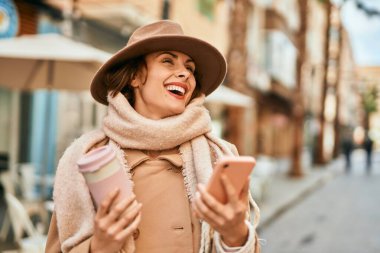 Genç İspanyol kadın akıllı telefon kullanıyor ve şehirde kahve içiyor..