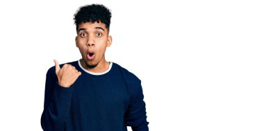 Gündelik giysiler giymiş genç Afro-Amerikan bir adam elleri yandan işaret ederek şaşırdı, ağzı açık hayret içinde kaldı.. 