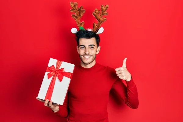 Νεαρός Ισπανόφωνος Άνδρας Φορώντας Χαριτωμένα Κέρατα Ταράνδου Χριστούγεννα Κρατώντας Δώρα — Φωτογραφία Αρχείου