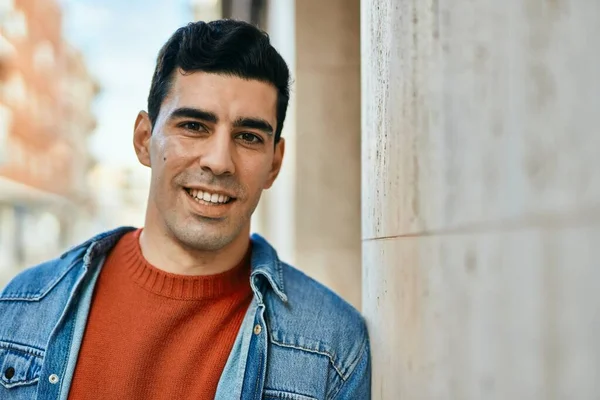 Genç İspanyol adam gülümseyerek şehirde mutlu mesut dikiliyor..