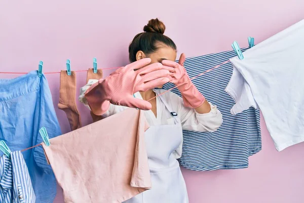 美丽的黑发女子用手捂住眼睛 在晾衣绳上洗衣服 用忧郁和恐惧的表情做停止动作 尴尬和消极的概念 — 图库照片