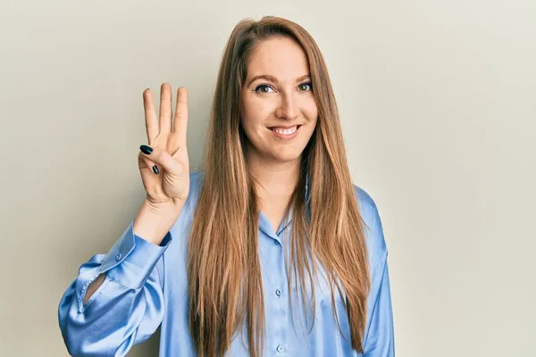 年轻的金发女人穿着休闲的蓝色衬衫 带着自信和快乐的笑容 手指着三号 — 图库照片