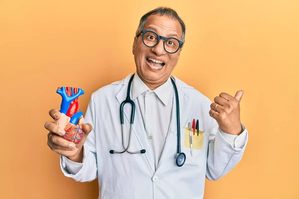 Middle Age Indian Man Wearing Doctor Uniform Holding Heart Pointing — ストック写真