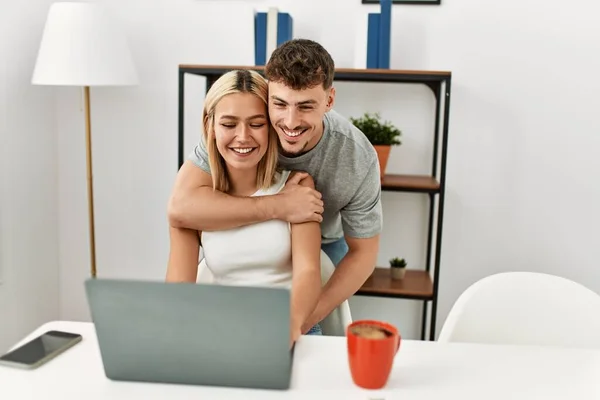 Giovane Coppia Caucasica Abbracciare Utilizzando Computer Portatile Seduto Sulla Scrivania — Foto Stock