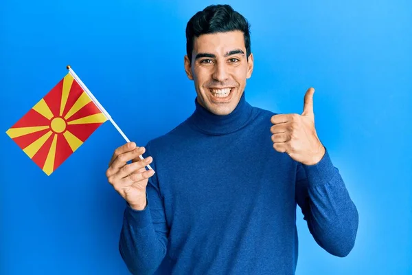 Bonito Hispânico Homem Segurando Bandeira Macedônio Sorrindo Feliz Positivo Polegar — Fotografia de Stock