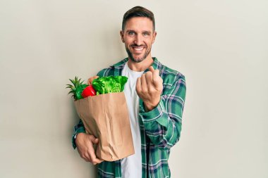 Sakallı yakışıklı bir adam, elinde poşetlerle seni çağırıyor. Gel buraya, elini salla, mutlu ol ve gülümse. 