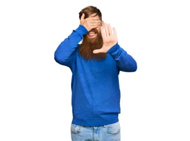 Genç İrlandalı kızıl adam, günlük kıyafetler giyip elleriyle gözlerini kapatıyor ve üzgün ve korku ifadeleriyle jest yapıyor. utangaç ve olumsuz kavram. 