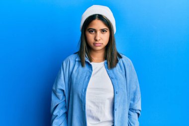 Tatlı yün şapka takan genç Latin kadın depresif ve endişeli, sinirli ve korkmuş bir şekilde ağlıyor. hüzünlü ifade. 