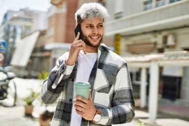 Genç İspanyol adam akıllı telefondan konuşuyor. Şehirde kahve içiyor..