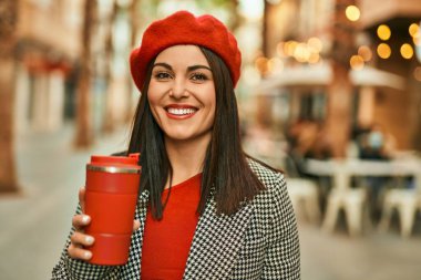 Genç İspanyol kadın gülümsüyor. Mutlu bir şekilde içiyor. Şehirde kahve içiyor..