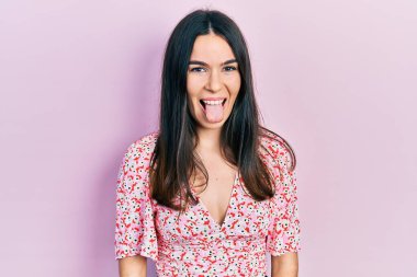 Yazlık elbise giyen genç esmer kadın komik bir ifadeyle dilini dışarı çıkartıyor. duygu kavramı. 