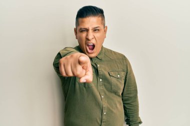 Gündelik kıyafetler giyen genç Latin adam kameraya kızgın ve sinirli bir şekilde seni işaret ediyor. 