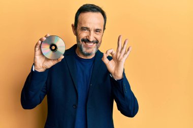 Orta yaşlı İspanyol bir adam diski tutuyor. Parmaklarıyla imza atıyor, gülümsüyor. Mükemmel bir sembol. 