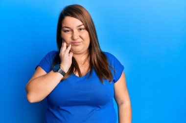 Güzel esmer, uzun boylu, günlük mavi tişört giyen, diş ağrısı ya da diş hastalığından dolayı ağzına dokunan eli ağrılı bir kadın. dişçi 