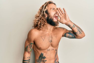 Sakallı, uzun saçlı, dövmeleri olmayan, eli ağızda bağıran ve bağıran yakışıklı bir adam. iletişim konsepti. 